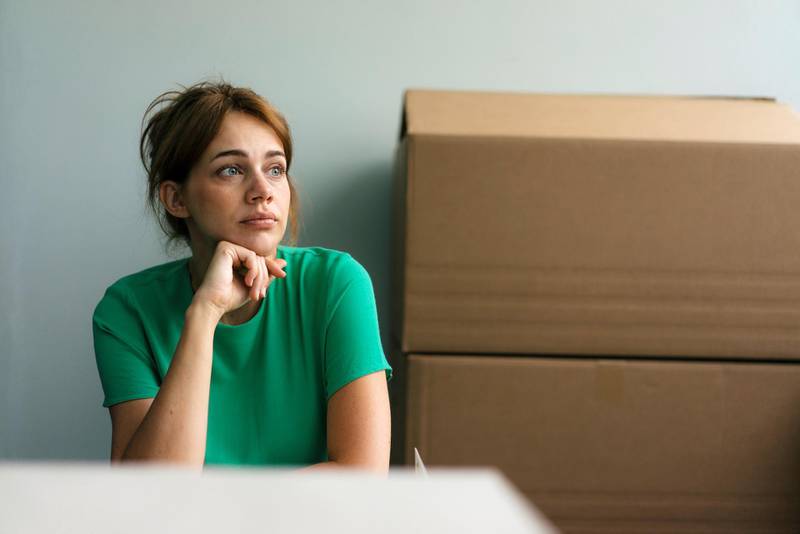 Thoughtful woman next to cardboard boxes in office
