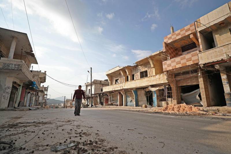 A Syrian man walks past damaged buildings in the town of Ihsim in the southern countryside of Idlib.  AFP