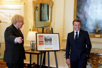 British Prime Minister Boris Johnson and French President Emmanuel Macron pose as they look at documents and artifacts related to former French President Charles de Gaulle during a visit at Downing Street in London. Reuters