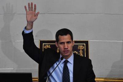 TOPSHOT - Venezuela's National Assembly head and self-proclaimed "acting president" Juan Guaido raises his hand to vote for the candidates he wants to be appointed as ambassadors in the countries that recognized him as Venezuela's interim president, at the National Assembly in Caracas on January 29, 2019.  The National Assembly met on Tuesday to debate a legal framework necessary to create a transitional government and call new elections, the opposition-controlled parliament also named 10 "diplomatic representatives" to countries that have recognized Juan Guaido as the country's interim president. As parliament met, Venezuela's attorney general asked the Supreme Court to bar Guiado from leaving the country and freeze his assets. 


 / AFP / Yuri CORTEZ
