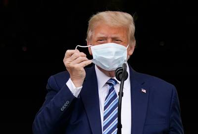President Donald Trump removes his face mask to speak from the Blue Room Balcony of the White House to a crowd of supporters in Washington. AP Photo