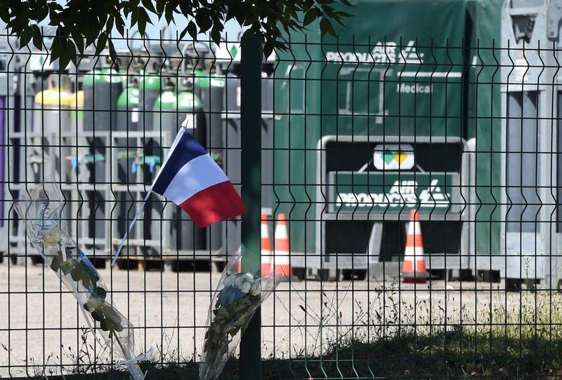 A French flag and flowers have been placed on the fence of the Air Products gas factory in Saint-Quentin-Fallavier near Lyon where the head of the decapitated man was found in an extremist attack. Philippe Desmazes/AFP Photo

