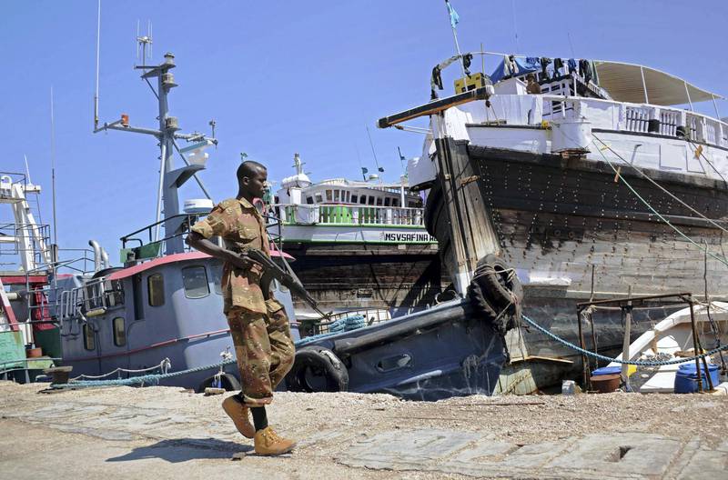 A Somali soldier walks past foreign ships in Bosaso harbor in Puntland on November 18, 2013. After increased security in Somalia's Puntland region, Bosaso has become a major export hub in the country. AFP PHOTO/Mohamed Abdiwahab (Photo by Mohamed Abdiwahab / AFP)