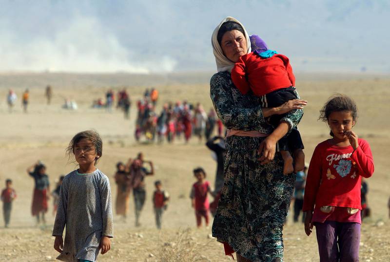 Displaced people from the minority Yazidi sect, fleeing violence from forces loyal to the Islamic State in Sinjar town, walk towards the Syrian border, on the outskirts of Sinjar mountain, near the Syrian border town of Elierbeh of Al-Hasakah Governorate, Iraq, August 11, 2014. Picture taken August 11, 2014. REUTERS/Rodi Said/File Photo SEARCH "POY DECADE" FOR THIS STORY. SEARCH "REUTERS POY" FOR ALL BEST OF 2019 PACKAGES. TPX IMAGES OF THE DAY.