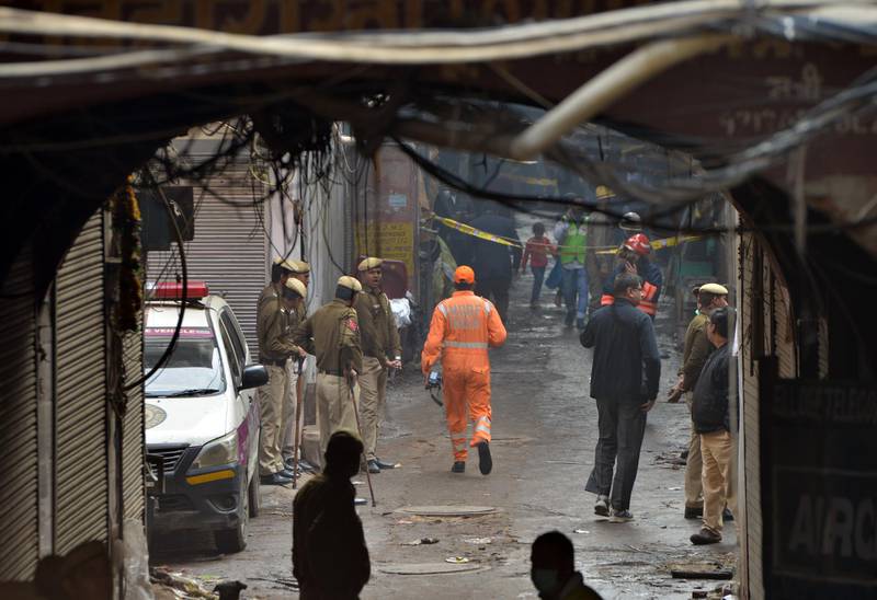 Indian police men stand in a lane as a National Disaster Response Force (NDRF) officer (C) walks the site where a fire broke out in New Delhi, India, 08 December 2019. According to news report, at least 40 people were killed after a  fire broke out at a building in New Delhi's Anaj Mandi area.  EPA