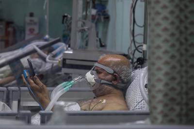 A Palestinian patient with coronavirus checks his mobile phone in the intensive care unit at the European Hospital, east of Rafah town, southern Gaza strip, 30 November 2020. The European Hospital, which has been classified as the Epidemiology Hospital since the start of the coronavirus in the Gaza Strip on 25 August 2020, has 334 infected cases under clinical care including 109 severe and critical cases. The production capacity of oxygen is 2,200 liters per minute, and there has become a large deficit after the increasing number of infections with Coronavirus.  EPA/MOHAMMED SABER