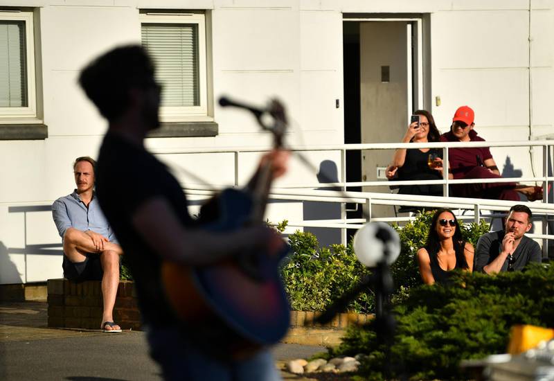 Residents of Prospect Quay socially distance as they watch Pete Martelle perform an impromptu gig to his apartment block in Putney, as the spread of the coronavirus continues, in London, UK on April 5, 2020. Reuters