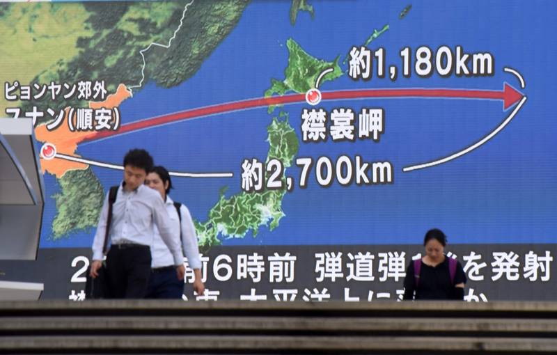 TOPSHOT - Pedestrians walk in front of a huge screen displaying a map of Japan (R) and the Korean Peninsula, in Tokyo on August 29, 2017, following a North Korean missile test that passed over Japan. 
Abe said on August 29 that he and US President Donald Trump agreed to hike pressure on North Korea after it launched a ballistic missile over Japan, in Pyongyang's most serious provocation in years.  / AFP PHOTO / Kazuhiro NOGI