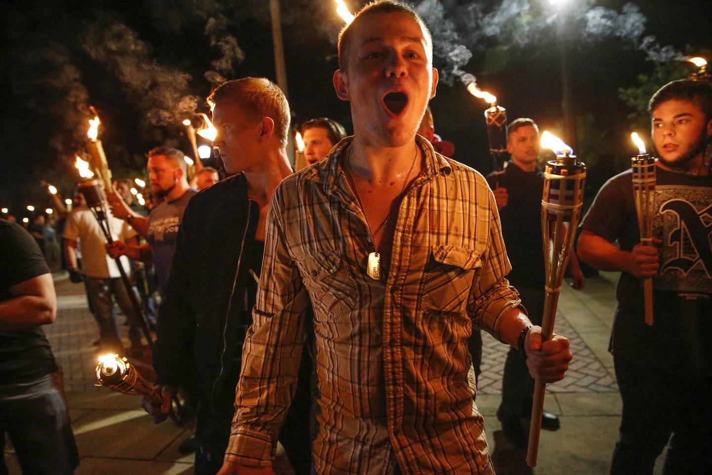 In this photo taken Friday, Aug. 11, 2017, multiple white nationalist groups march with torches through the UVA campus in Charlottesville, Va.   Hundreds of people chanted, threw punches, hurled water bottles and unleashed chemical sprays on each other Saturday after violence erupted at a white nationalist rally in Virginia.  (Mykal McEldowney/The Indianapolis Star via AP)