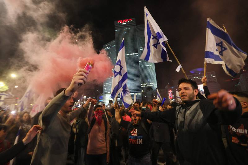 A protester in Tel Aviv lights a flare during a demonstration against the judicial overhaul bill. AFP