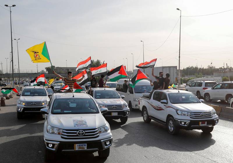Members of Kataib Hezbollah paramilitary group wave flags and travel in vehicles as they take part in a parade ahead of the annual Quds Day, or Jerusalem Day, during the Muslim holy month of Ramadan, in Baghdad, Iraq May 6, 2021. REUTERS/Thaier Al-Sudani
