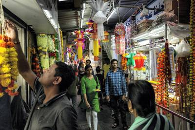 DUBAI, UNITED ARAB EMIRATES. 24 OCTOBER 2019. Worshippers pass by Hindu shops while on their way to the Hindu Temple. As the Hindu Festival of Diwali starts in the UAE, devotees flok to the Hindu Temple in Bur Dubai to worship. Adjacent to the Temple is what is commonly refered to “Hindi Lane”, a small corridor of shops selling flowers, offerings and general items for Hindu ceremonies. Diwali, Deepavali or Dipavali is a four-to-five day-long festival of lights, which is celebrated by Hindus, Jains, Sikhs and some Buddhists every autumn in the northern hemisphere. (Photo: Antonie Robertson/The National) Journalist: None. Section: National.
