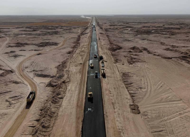 Workers paving a road as part of a project in the central Iraqi Najaf governorate, of a land route that will link Najaf to Saudi Arabia. AFP