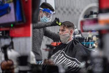 A hairdresser, wearing gloves, a protective face mask and a face shield, cuts the hair of a client in Vienna. EPA