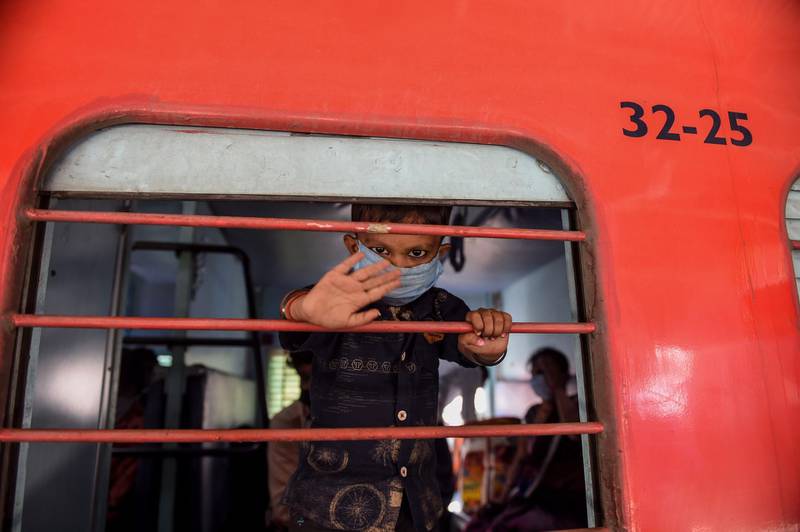 A young boy from a migrant workers' family waves from a railway compartment before the departure of a special train to Agra in Uttar Pradesh state during a government-imposed nationwide lockdown as a preventive measure against the coronavirus, at Sabarmati Railway Station on the outskirts of Ahmedabad. AFP