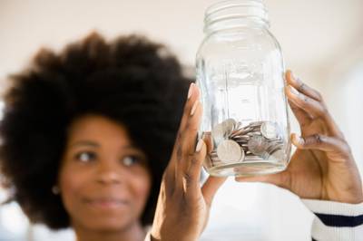 Mixed race woman holding jar of change. Getty Images
