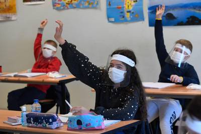 Schoolchildren wearing protective mouth masks and face shields attend a course in a classroom at Claude Debussy college in Angers, western France after France eased lockdown measures to curb the spread of the COVID-19 pandemic, caused by the novel coronavirus.    AFP