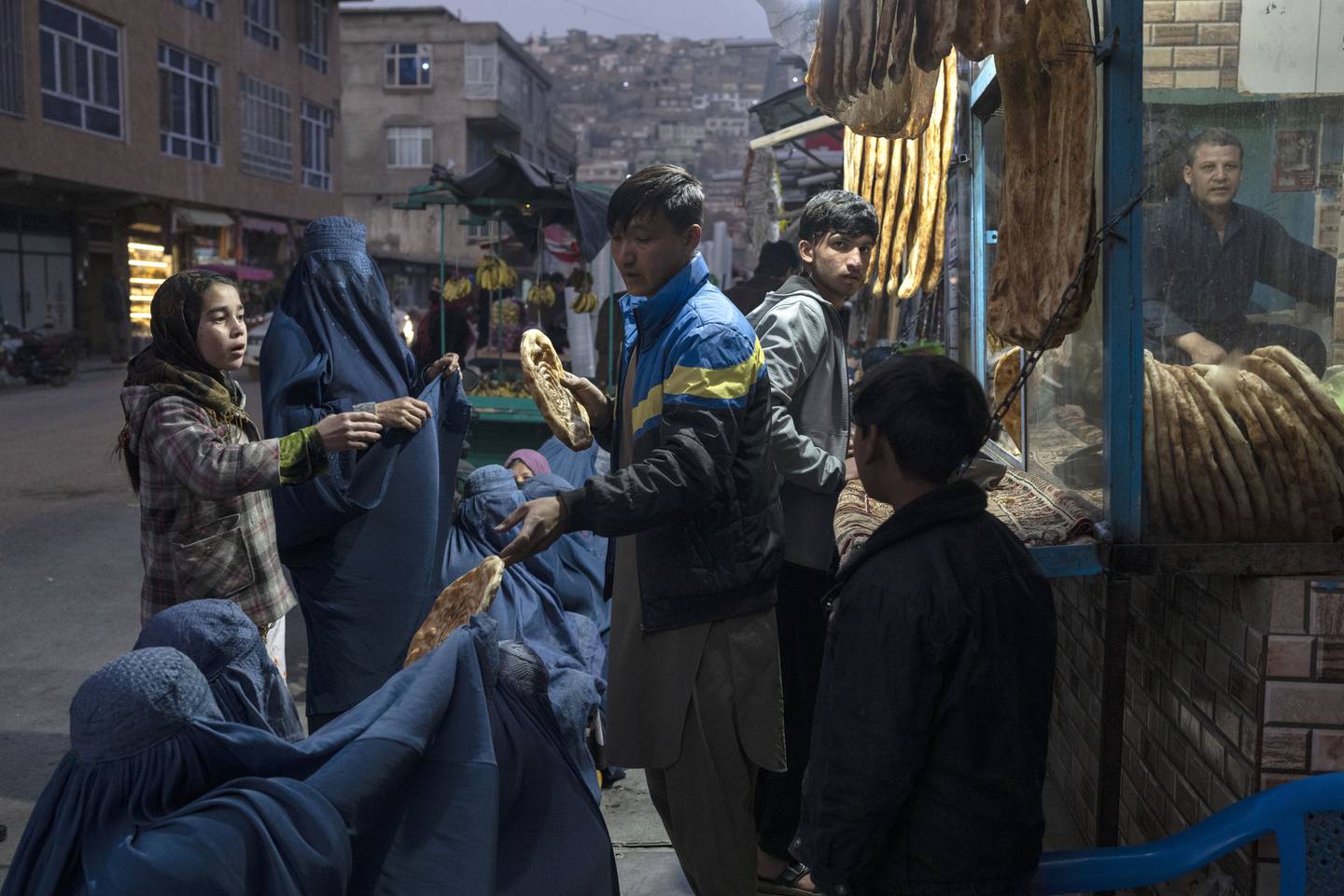 A man distributes bread to Afghan women outside a bakery in Kabul, Afghanistan, on December 2. AP