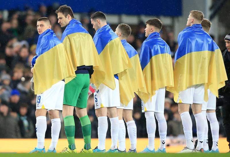 Vitaliy Mykolenko (L) and teammates stand draped in national flags of Ukraine. AFP