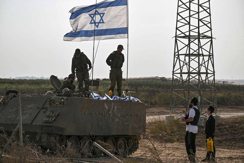 Israeli soldiers on an armoured vehicle speak an ultra-orthodox man, as they deploy near Israel's border with the Gaza Strip. AFP