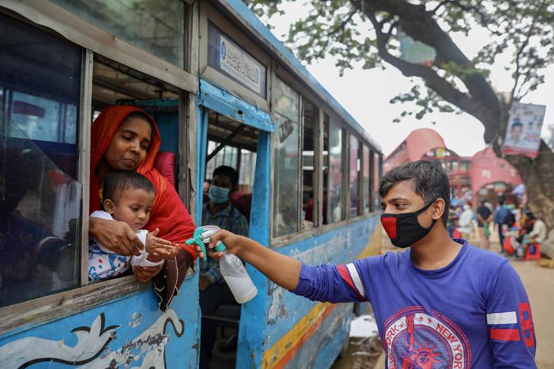 A man sprays hand sanitiser on a child who is travelling on a public bus in Dhaka, Bangladesh. Reuters