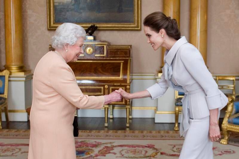 Hollywood star Angelina Jolie is presented with the Insignia of an Honorary Dame Grand Cross of the Most Distinguished Order of St Michael and St George by Queen Elizabeth at Buckingham Palace in 2014. Getty Images