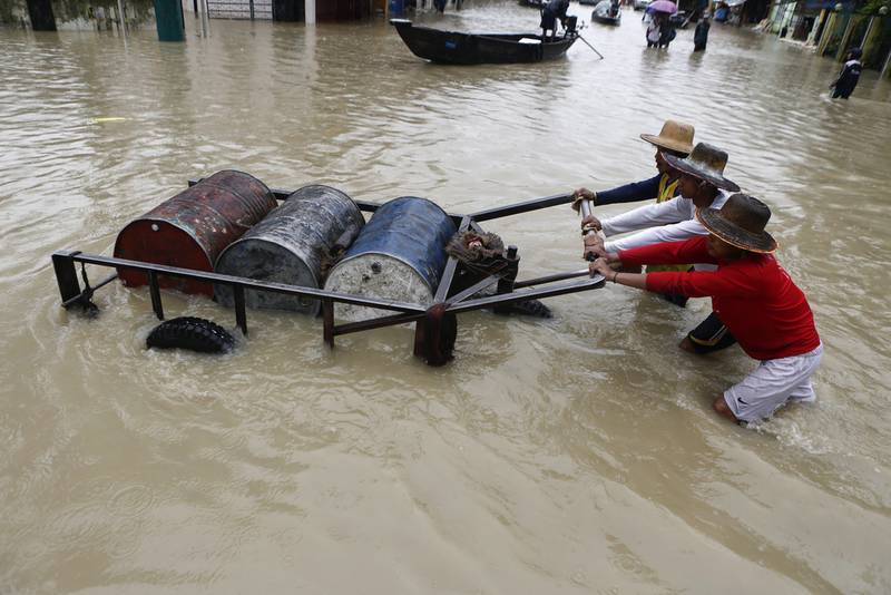 Workers push a cart loaded with fuel barrels along a flooded road in Pathein City, capital of Myanmar's Ayeyarwady region. More than 300,000 people were affected by flooding that submerged 703 villages, forcing 38,000 to take refuge in about 180 local shelters in the region. EPA