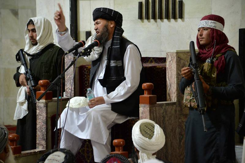 Armed Taliban fighters stand next to a religious leader, speaking during Friday prayers at the Pul-e Khishti Mosque in Kabul. EPA