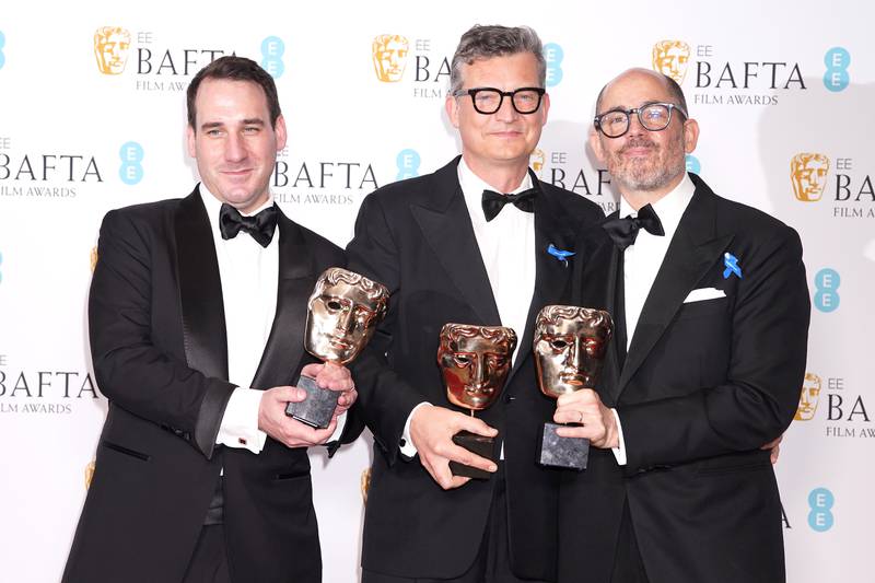 From left, cinematographer James Friend, producer Malte Grunert and director Edward Berger celebrate their win for All Quiet on the Western Front. PA