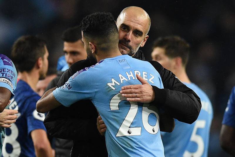 Manchester City's Spanish manager Pep Guardiola (R) embraces Manchester City's Algerian midfielder Riyad Mahrez on the pitch. AFP