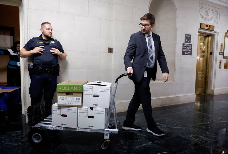 US House Ways and Means Committee staff members transport boxes of documents after a meeting to discuss Mr Trump's tax returns in Washington on December 20, 2022. Reuters