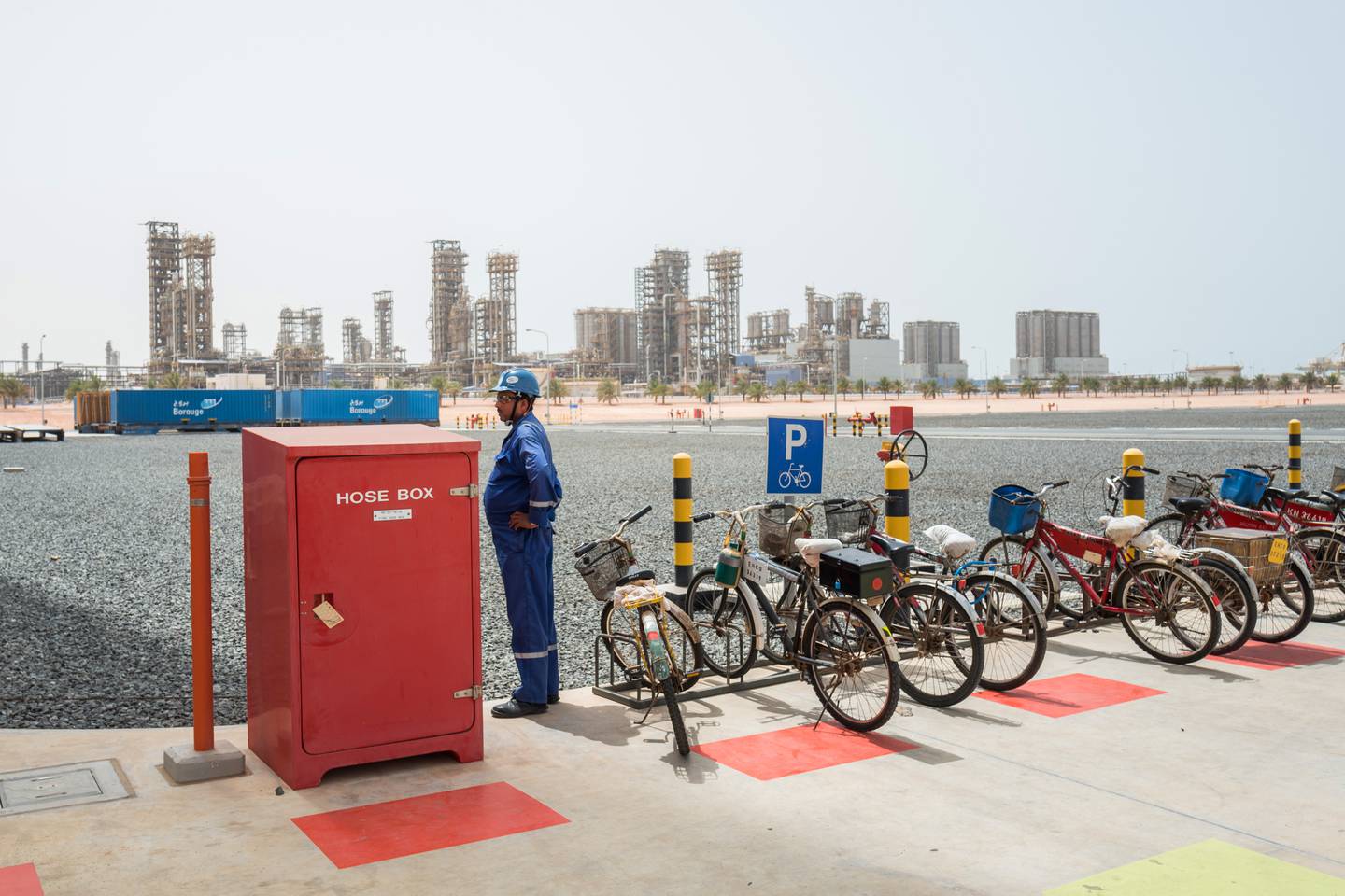 An employee stands beside a fire hose box and bicycle park at the Ruwais refinery and petrochemical complex, operated by Abu Dhabi National Oil Co. (ADNOC), in Al Ruwais, United Arab Emirates, on Monday, May 14, 2018. Adnoc is seeking to create world’s largest integrated refinery and petrochemical complex at Ruwais. Photographer: Christophe Viseux/Bloomberg