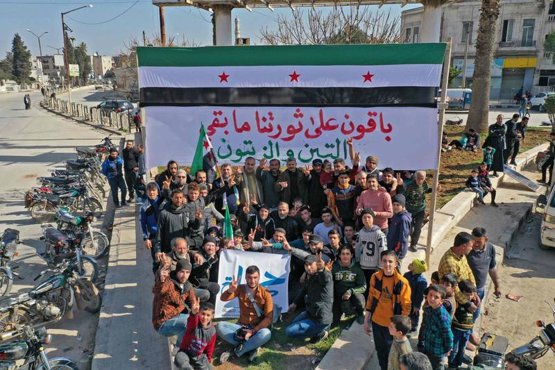 Syrians take part in an anti-government demonstration in Idlib city, north-west Syria. The message on the sign behind them says: "We shall continue our revolution as long as there are figs and olives." AFP