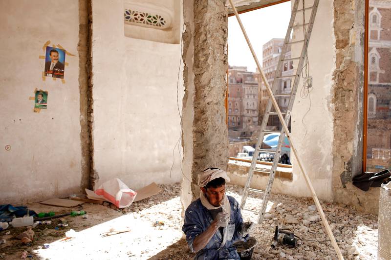 SANA'A, YEMEN - February 2, 2010: Yemen President, Ali Abdallah Salih's picture on the wall overlooks a man lighting a cigarette while renovates a building in the old city of Sana'a, Yemen. ( Ryan Carter / The National ) 

 *** Local Caption ***  al22fe-YemenOasis7.jpg
