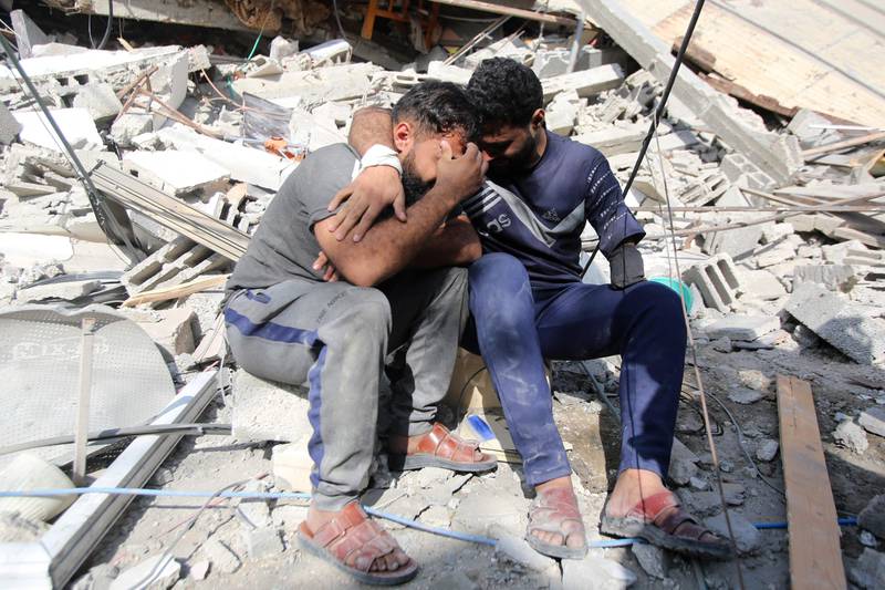 Palestinians mourn as they sit among rubble in Gaza city's Shati refugee camp, amid continuing battles between Israel and the Palestinian Hamas movement. AFP