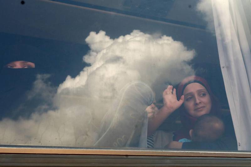 Syrian refugees wave through the windows of a bus as they prepare to leave the Lebanese capital Beirut to return to their homes in Syria on September 9, 2018. - A group of Syrian refugees left the Lebanese capital for their homeland on September 9 as part of an organised operation coordinated between Lebanese and Syrian authorities. (Photo by ANWAR AMRO / AFP)