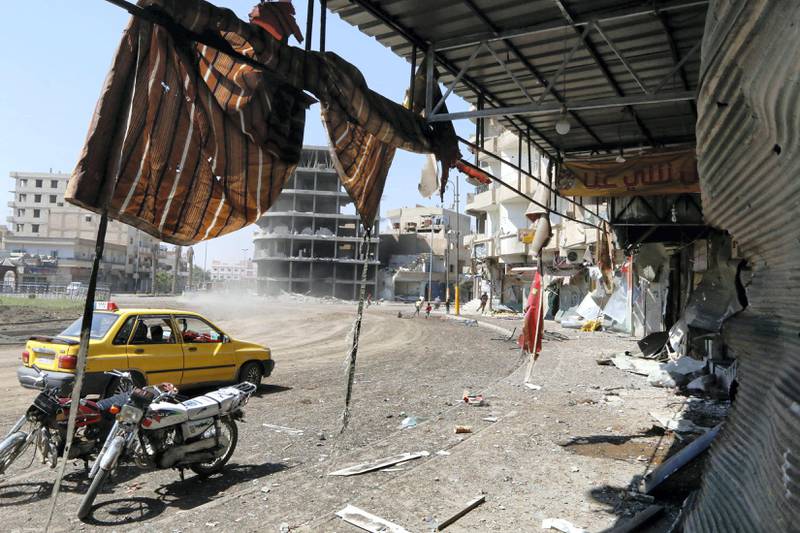 A car drives by shops damaged by what activists claim is shelling from forces loyal to Syria's President Bashar al-Assad on Al-Naeem square in central Raqqa August 29, 2014. REUTERS/Stringer (SYRIA - Tags: POLITICS CIVIL UNREST CONFLICT) - GM1EA8T1QUJ02