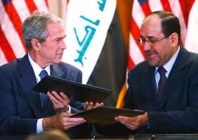 US president George W Bush and Iraqi prime minister Nouri Al Maliki exchange official documents on December 14, 2008 in Baghdad. Mr Bush had arrived in Iraq on an unannounced farewell visit, weeks before leaving office.