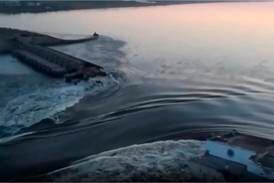 Water runs through a breakthrough in the Kakhovka dam in Kakhovka. AP