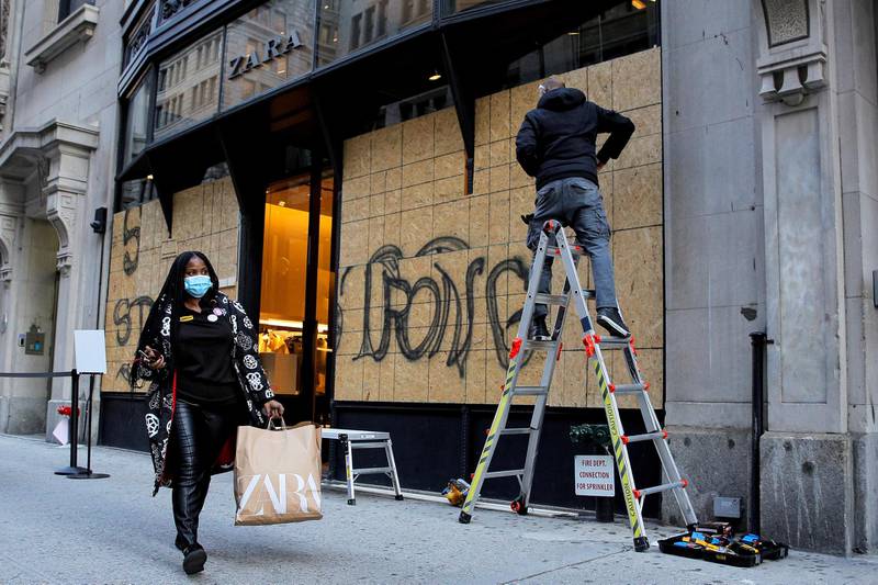 A shopper passes as workers board up a store ahead of election results in the Manhattan borough of New York. REUTERS