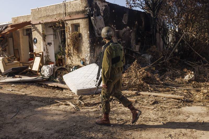 An Israeli soldier passes homes destroyed during fighting with Hamas militants in Kfar Aza kibbutz, Israel. Bloomberg