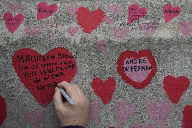 A woman writes a message in a red heart on the wall. AP Photo