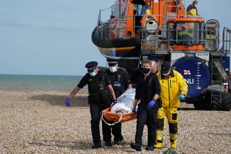 Police officers and members of the Royal National Lifeboat Institution carry a person from a boat ashore in Kent. PA