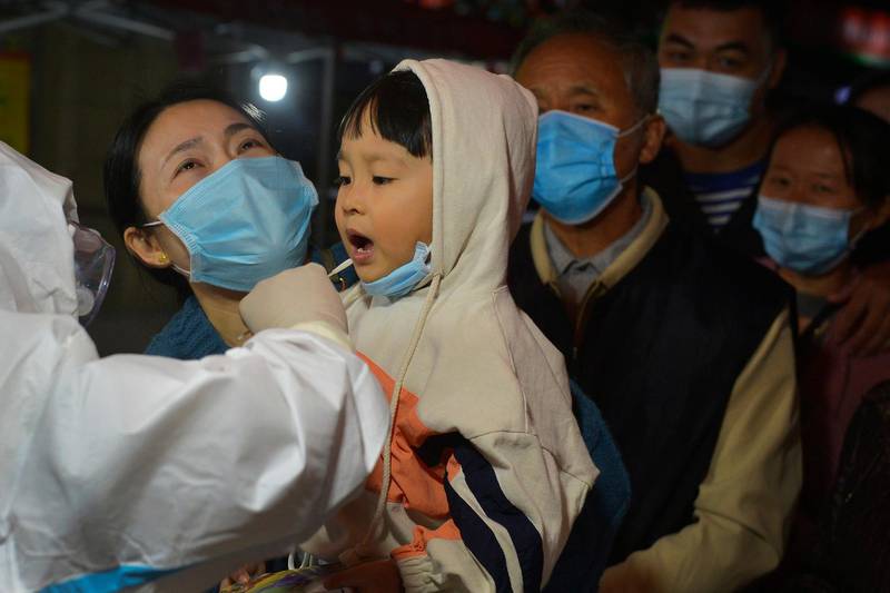 A medic takes a swab from a child as residents line up for coronavirus tests in  Qingdao in east China's Shandong province. AP Photo