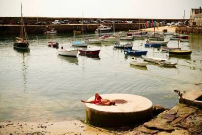 A man sunbathes at the harbour in Mousehole, Cornwall. AP