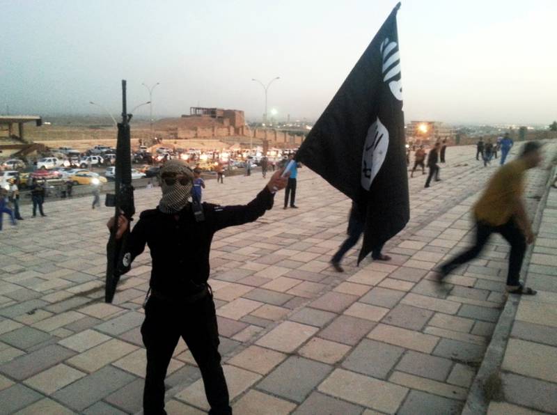 FILE PHOTO: A fighter of the Islamic State of Iraq and the Levant (ISIL) holds an ISIL flag and a weapon on a street in the city of Mosul, Iraq, June 23, 2014.   To match Special Report MIDEAST-CRISIS/IRAQ-MOSUL    REUTERS/Stringer/File Photo