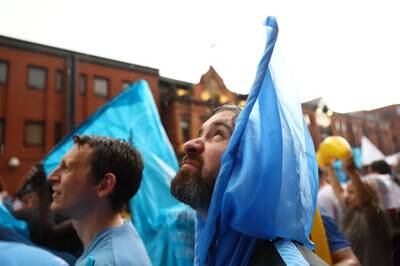 A Manchester City fan looks upwards towards the rain clouds as the parade is delayed due to bad weather. Reuters