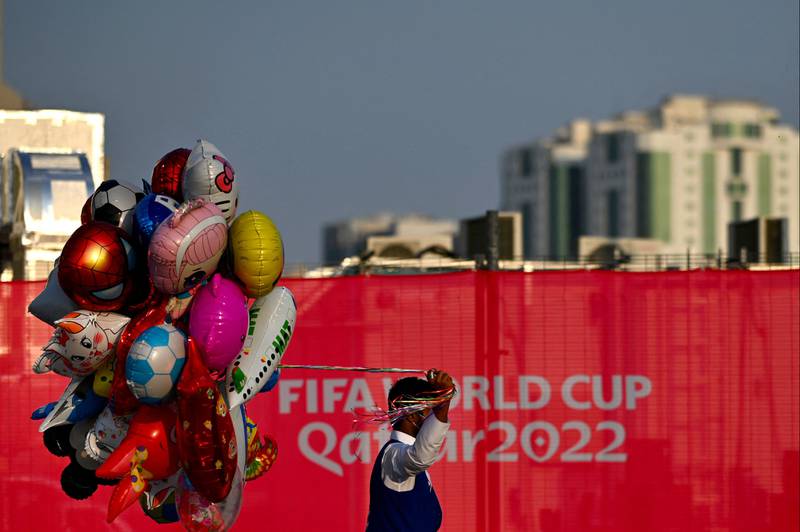 A man sells balloons in Doha as a sign shows the anticipation for the 2022 World Cup. AFP