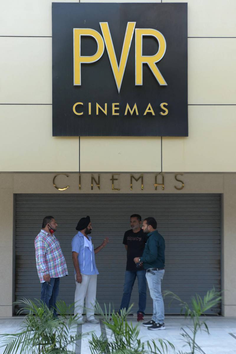 People stand outside a closed cinema theatre in Amritsar on October 15, 2020, with some states still keeping theatres closed amid Covid-19 coronavirus pandemic. (Photo by NARINDER NANU / AFP)