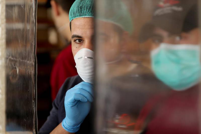 FILE PHOTO: Palestinians, wearing masks as a preventive measure against the coronavirus disease, work in a bakery in Gaza City March 22, 2020. REUTERS/Mohammed Salem/File Photo